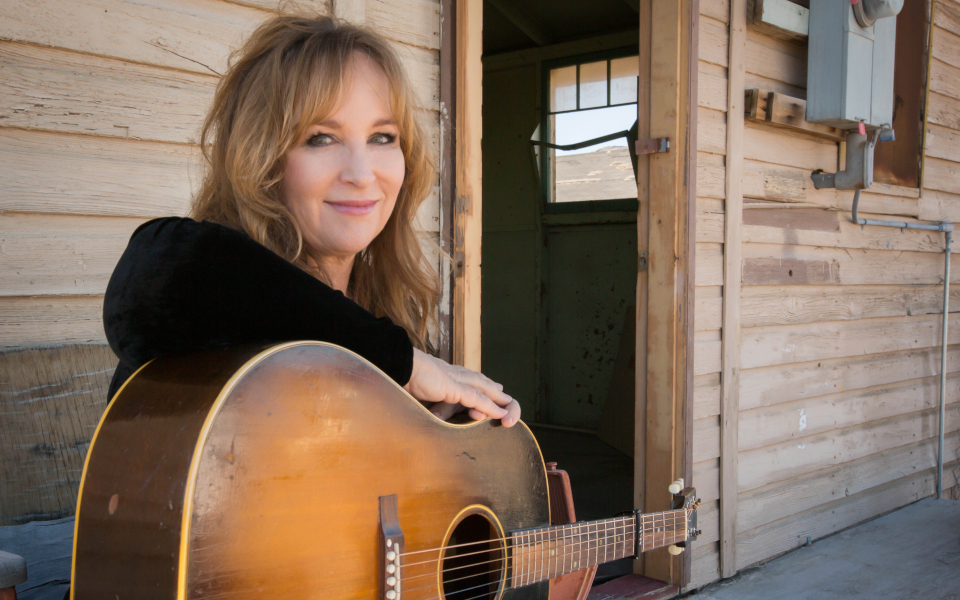 Gretchen Peters Gretchen Peters smiling and leaning on her acoustic guitar
