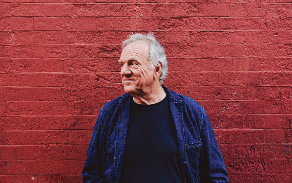 Ralph McTell Ralph McTell faces off camera and stands in front of a red brick wall