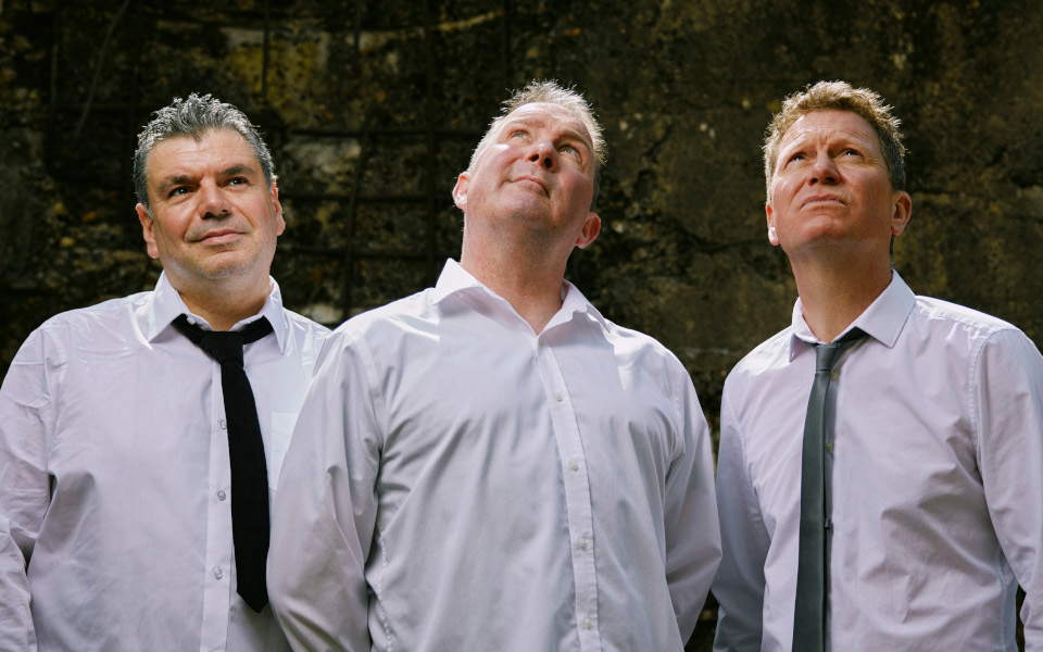 Frost* The band Frost* all three members are wearing white shirts and looking up.