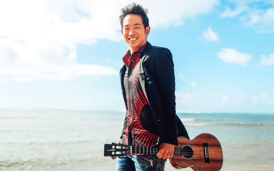 Jake Shimabukuro Jake Shimabukuro on the beach with his ukulele smiling
