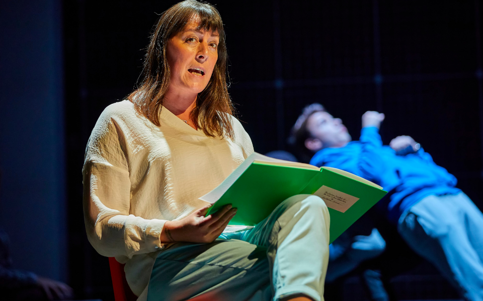 Rebecca Root in The Curious Incident of the Dog in the Night-Time Rebecca Root sits reading a book